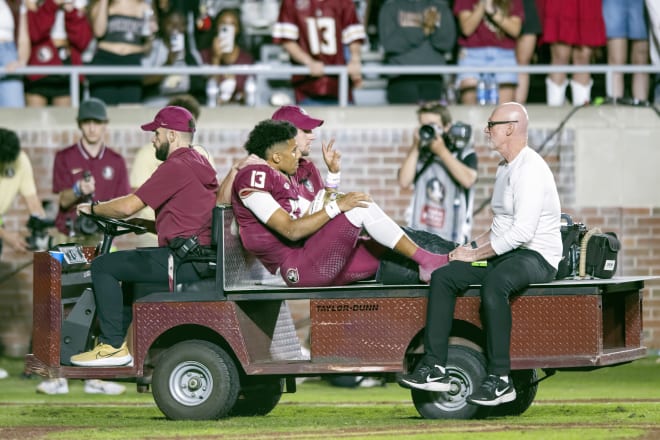 Jordan Travis signals to the crowd as he is carted off the field Saturday.