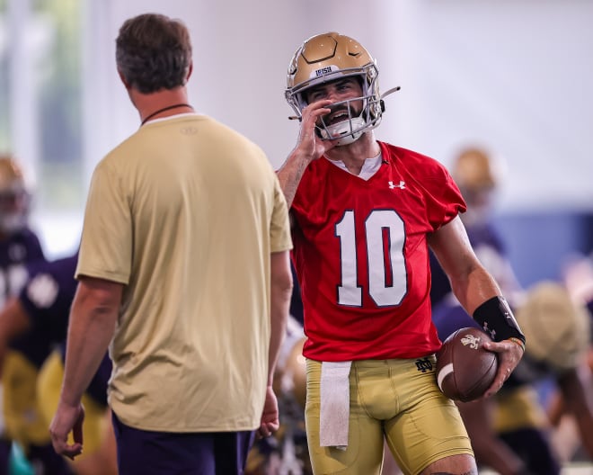 Notre Dame quarterback Sam Hartman chats with QBs coach Gino Guidugli during the first day of preseason training camp on July 26.