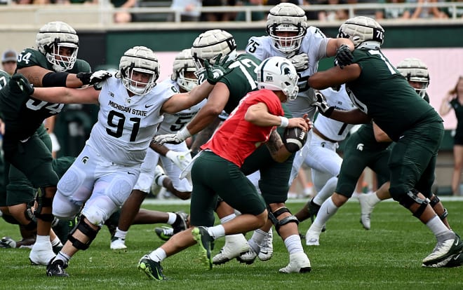 Defensive tackle Alex VanSumeren (No. 91) forces quarterback Noah Kim (No. 14) out of the pocket during scrimmage at Spartan Stadium. 