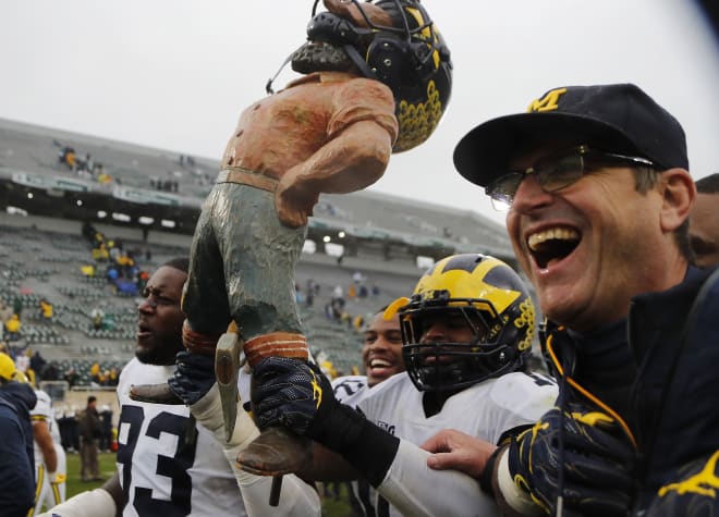 Michigan Wolverines football head coach Jim Harbaugh celebrates with his players after Michigan's win over MSU.