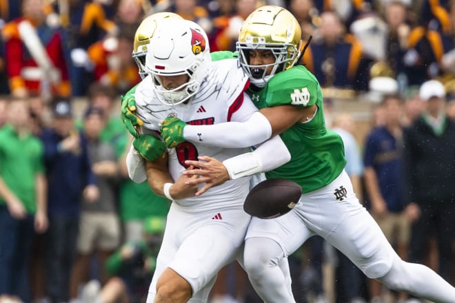 Notre Dame freshman cornerback Leonard Moore (right) strips the ball from Louisville QB Tyler Shough for a big turnover for the Irish Saturday at Notre Dame Stadium.