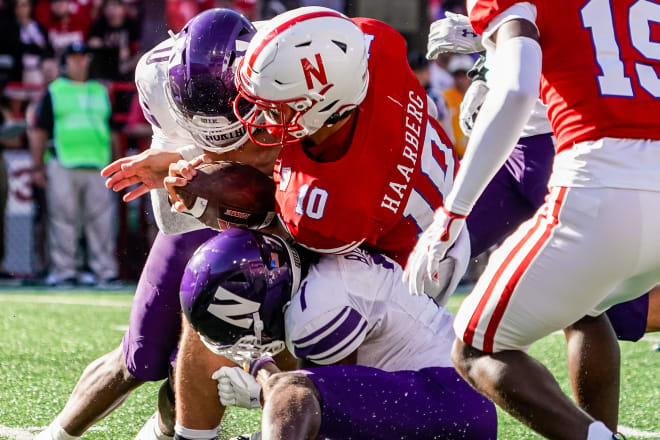 Senior safety Coco Azema (left) delivers a big hit on Nebraska quarterback Heinrich Haarberg, with help from Ore Adeyi..