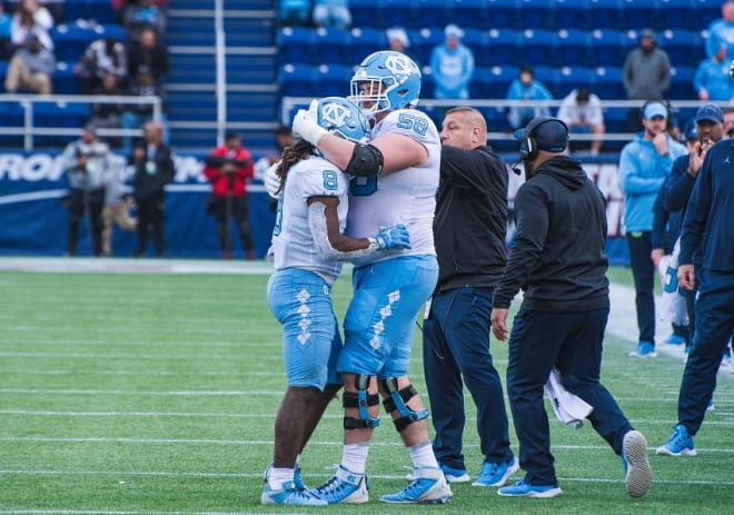 Three Tar Heels reached the 1,000-yard mark Friday, including Michael Carter, pictured being greeted by teammate Nick Polino. in Annapolis.