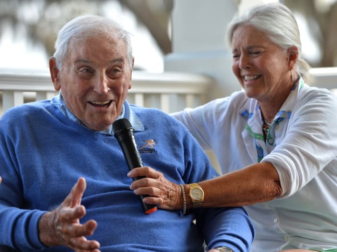 Mary Lujack, right, holds a microphone for her father, Johnny Lujack, winner of the 1947 Heisman Trophy at Sarasota, Florida's The Founder's Club in 2022.
