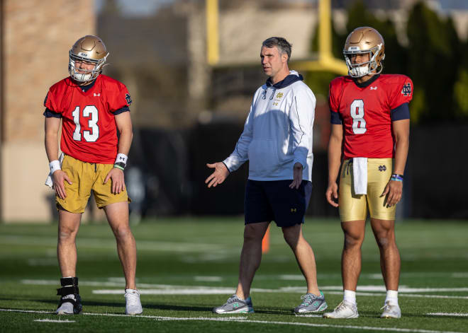 Notre Dame QB Riley Leonard (13) wears a TayCo brace over his right shoe during a spring practice drill, with QBs coach Gino Guidugli and QB Kenny Minchey (8).