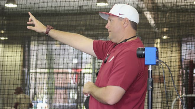 FSU pitching coach Micah Posey instructs. Next to him is a slow-mo Edgertronic camera. 