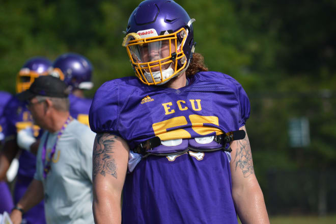 Senior ECU offensive lineman Garrett McGhin listens on as Don Mahoney gives technique instruction on First Tuesday.