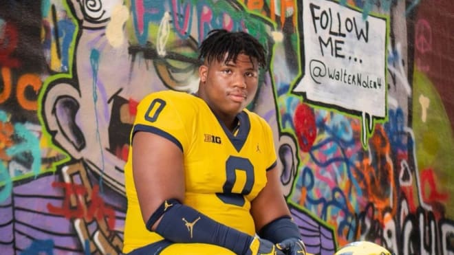 Five-star defensive tackle Walter Nolen holds a Michigan Wolverines football recruiting, Jim Harbaugh.