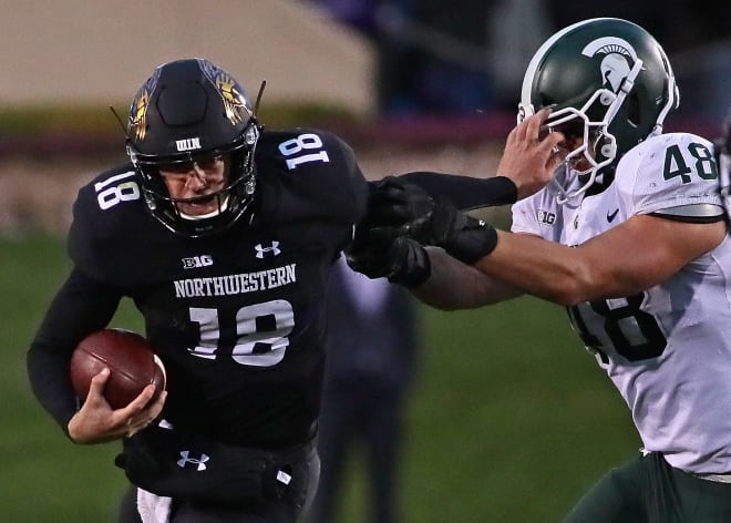 NU quarterback Clayton Thorson helps a Michigan State defender honor the school's "I didn't see anything" policy. 