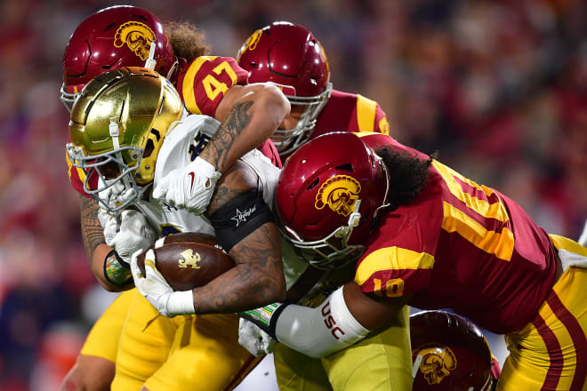 UsC senior linebacker Ralen Goforth (right, 10) tackles Notre Dame running back Logan Diggs. 