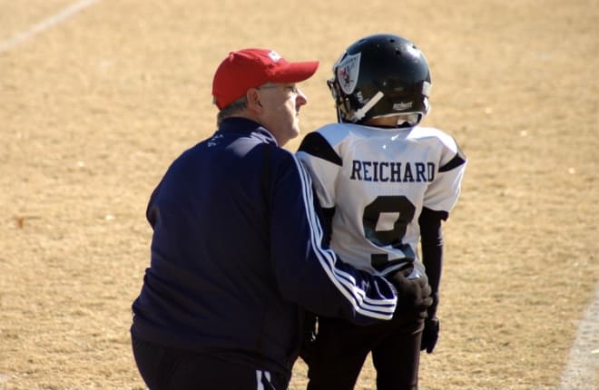 The late Gary Reichard, left, talks to his son Will during a pee-wee football game. Photo courtesy of Dana Reichard 