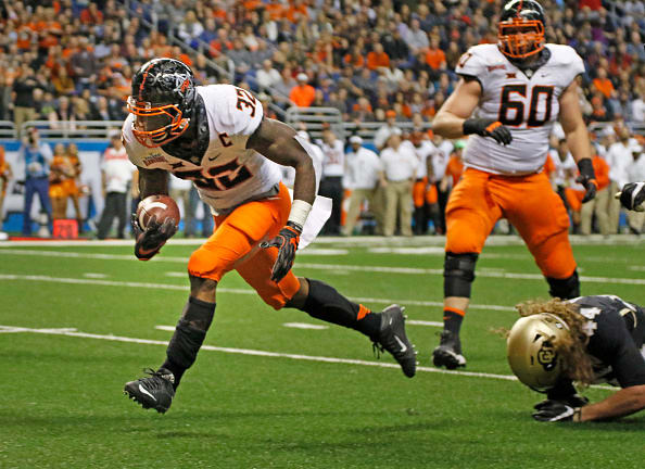 SAN ANTONIO,TX - DECEMBER 29: Chris Carson #32 of the Oklahoma State Cowboys eludes the tackle of Addison Gillam #44 of the Colorado Buffaloes for his team first touchdown in the Valero Alamo Bowl at the Alamodome on December 29, 2016 in San Antonio, Texas. (Photo by Ronald Cortes/Getty Images)