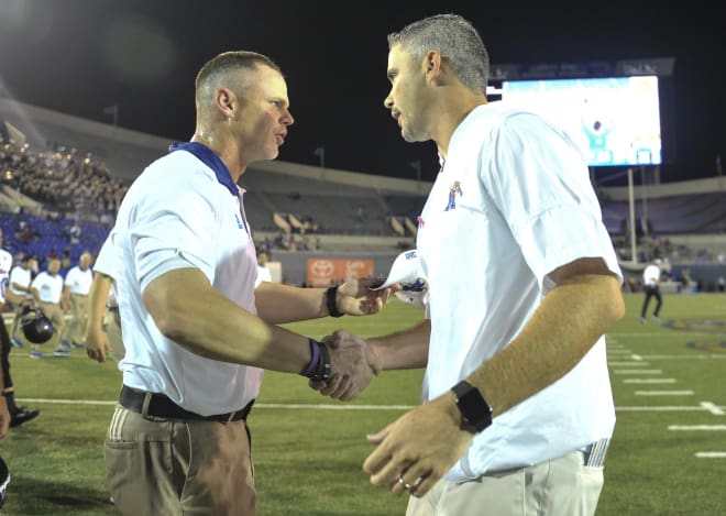 Tulsa head coach Philip Montgomery (left) meets Memphis coach Mike Norvell at midfield after TU beat the Tigers 59-30 in Memphis last season.