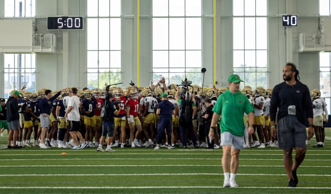 Notre Dame coach Marcus Freeman is surrounding by his Irish football team during a mid-practice pep talk. 