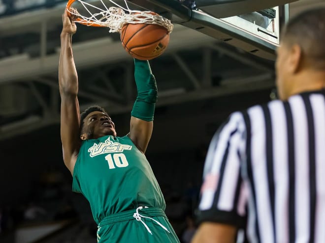 USF Bulls forward Alexis Yetna finishes a dunk while an official looks on.