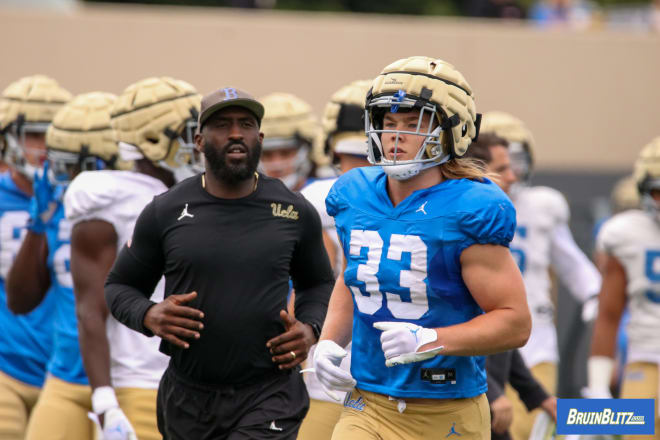 UCLA running back Carson Steele (33), seen here running alongside position coach DeShaun Foster earlier in spring camp, co-headlines a deep group along with sophomore T.J. Harden.