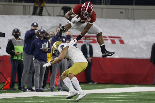 Alabama Crimson Tide football senior running back Najee Harris leaps over Notre Dame Fighting Irish football fifth-year senior quarterback Nick McCloud