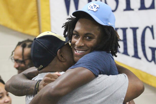Seen here embracing assistant coach DeCarlos Mitchell, Western Branch receiver Paul Billups will take his talents to Chapel Hill to play College Football at North Carolina in the ACC