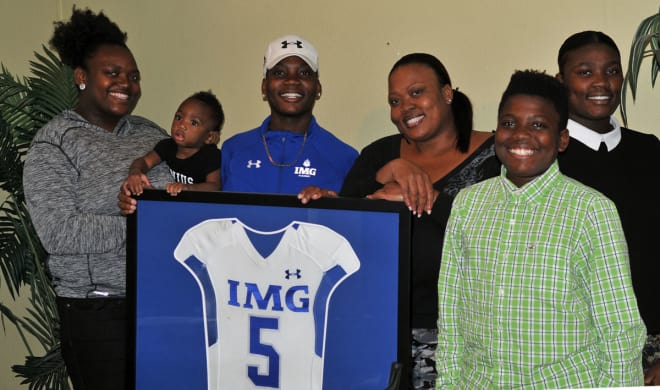 Janice Francois, four children and grandson pose for a portrait around Deondre's framed IMG Academy jersey.