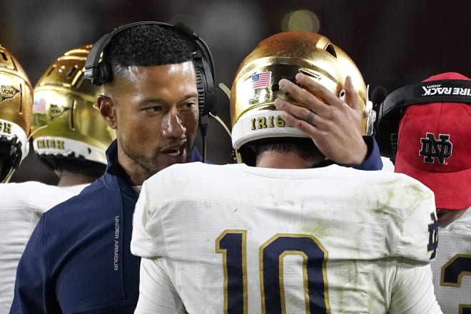 Notre Dame coach Marcus Freeman (left) chat with QB Drew Pyne on the Irish sideline.