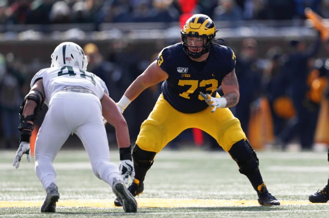 Michigan Wolverines football offensive tackle Jalen Mayfield blocks a defender