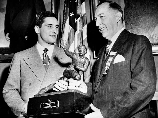 Notre Dame quarterback Johnny Lujack, left, receives the Heisman Trophy from Wilbur Jurden, president of the Downtown Athletic Club in New York, Dec. 10, 1947. Lujack, who led Notre Dame to three national championships in the 1940s, died Tuesday at the age of 98.