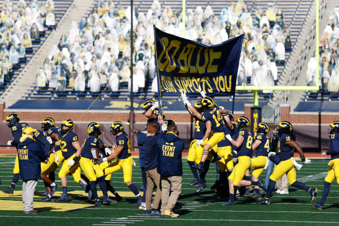 Michigan Wolverines football touches the banner in front of an empty Michigan Stadium