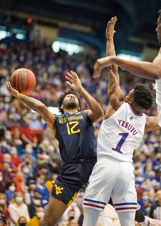 West Virginia Mountaineers guard Taz Sherman (12) shoots as Kansas Jayhawks guard Joseph Yesufu (1) defends during the first half at Allen Fieldhouse.