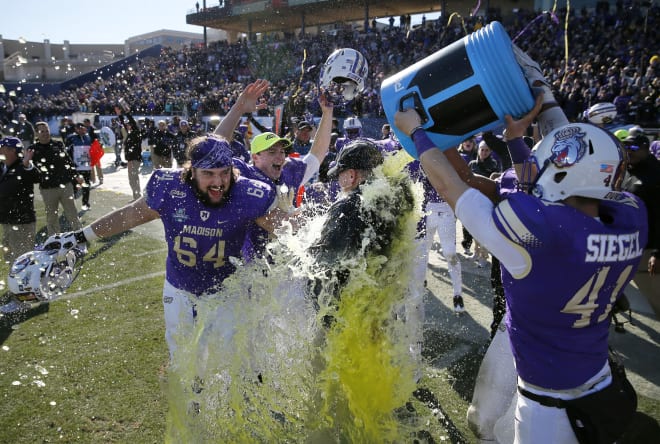 James Madison football players celebrate with coach Mike Houston (center) after winning the FCS national championship in January.