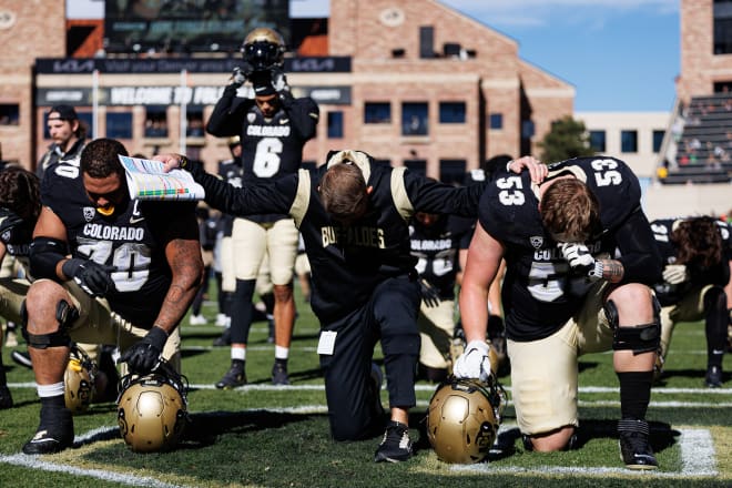 Colorado head coach Mike Sanford prays with offensive linemen Casey Roddick and Noah Fenske prior to kickoff.