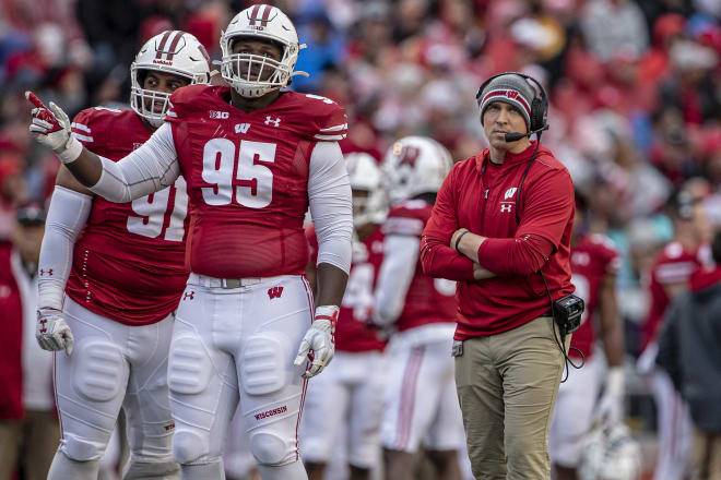 Nose tackles Bryson Williams (91) and Keeanu Benton (95) chat with Wisconsin defensive coordinator Jim Leonhard during a 2019 game.