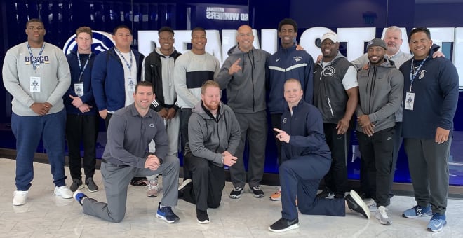 The group from St. John Bosco pose with multiple members of Penn State's coaching staff before leaving campus Tues.