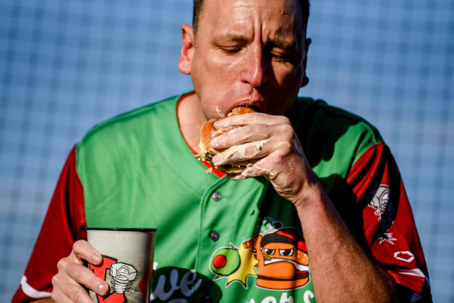 Nathan's Hot Dog Eating champion Joey Chestnut eats an olive burgers before the Lugnuts game against the TinCaps on Thursday, Aug. 10, 2023, at Jackson Field in Lansing. Chestnut set a record with 13 olive burgers eaten in 5 minutes.