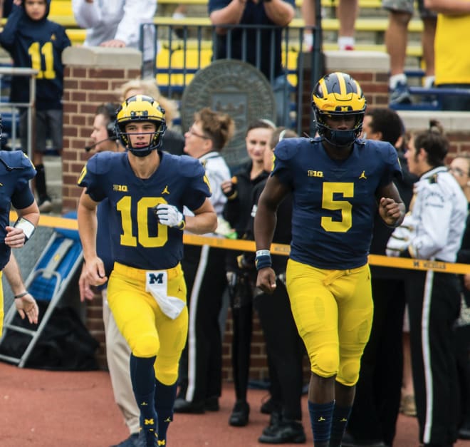 Michigan Wolverines quarterbacks Dylan McCaffrey and Joe Milton run onto the field