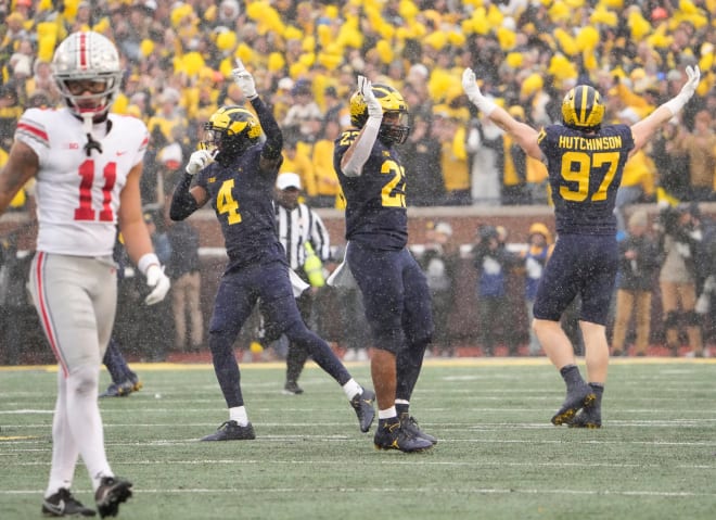 Michigan Wolverines defensive end Aidan Hutchinson (97), linebacker Michael Barrett (23) and defensive back Vincent Gray (4) celebrate behind Ohio State Buckeyes wide receiver Jaxon Smith-Njigba (11) during the fourth quarter of the NCAA football game at Michigan Stadium in Ann Arbor on Saturday, Nov. 27, 2021. Ohio State lost 42-27