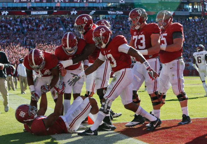 Alabama players look to help Alabama tight end O.J. Howard (88) to his feet after he took a big hit while scoring a touchdown during the Crimson Tide's 33-14 win over Texas A&M Saturday October 22, 2016.