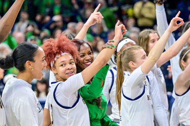 Current Notre Dame point guard Hannah Hidalgo (red hair) and coach Niele Ivey (in green) celebrated an NCAA Tourney win Monday with the rest of the Irish team.