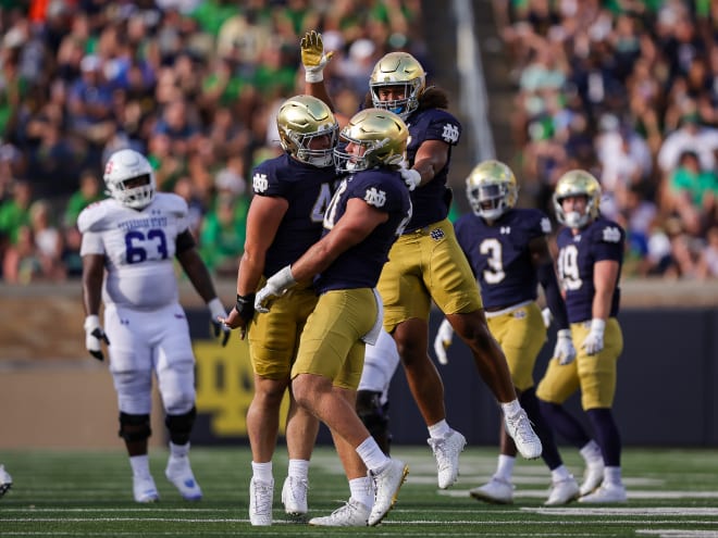 Notre Dame defensive end Joshua Burnham celebrates with defensive tackle Donovan Hinish, left, and defensive end Junior Tuihalamaka, back.