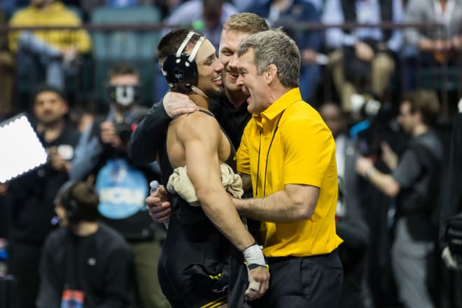 Real Woods celebrates with Iowa head coach Tom Brands and assistant coach Ryan Morningstar. 