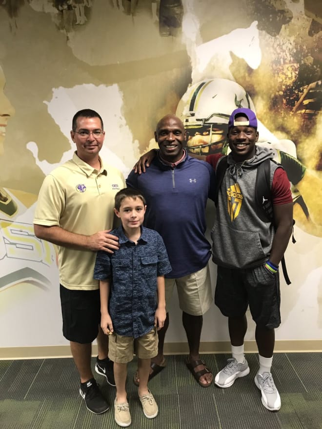 Cherry's coach, coach's son, Charlie Strong and Cherry pose at USF on Thursday