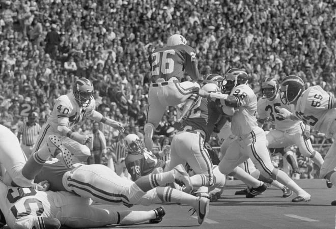 Wisconsin's Bill Marek (26) takes a leap over teammate Ken Starch (32) for two yards during play against Michigan, in Madison, Wisconsin, Sept. 13, 1975.