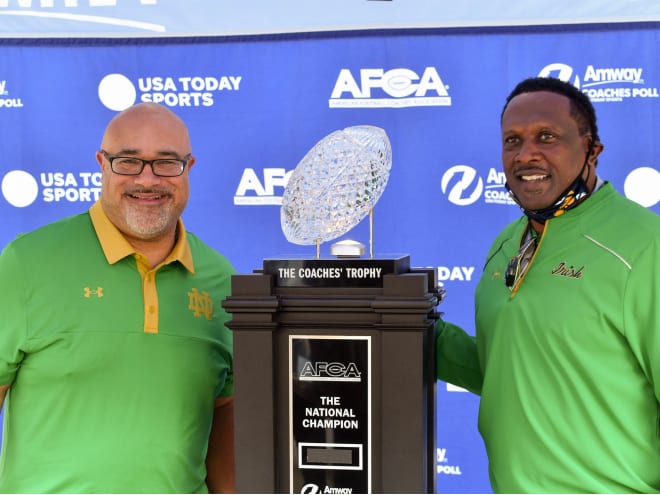 Former Notre Dame football players Chris Zorich, left, and Tim Brown pose with The AFCA Coaches' Trophy in 2020.
