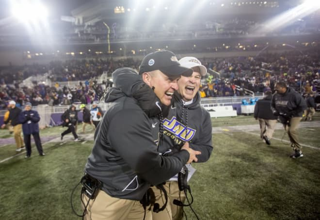 Former James Madison coach Mike Houston (left) and offensive line coach Bryan Stinespring celebrate the Dukes' win over Weber State in the 2017 FCS quarterfinals at Bridgeforth Stadium in Harrisonburg.