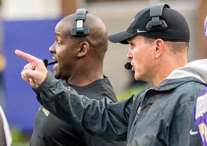James Madison coach Mike Houston (right) and inside linebackers coach Byron Thweatt talk on the sideline during an Oct. game against William & Mary in Harrisonburg.