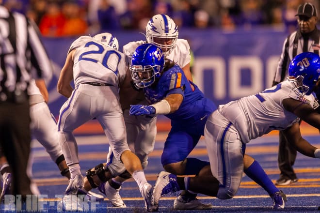 Air Force running back,  Brad Roberts (20) powers into the line before being tackled by Boise State MLB, DJ Schramm (52) Saturday night in Boise.