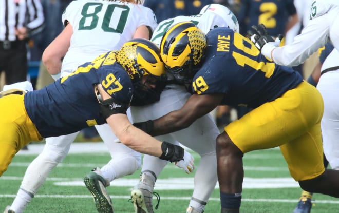 Michigan Wolverines defensive ends Aidan Hutchinson and Kwity Paye make a tackle