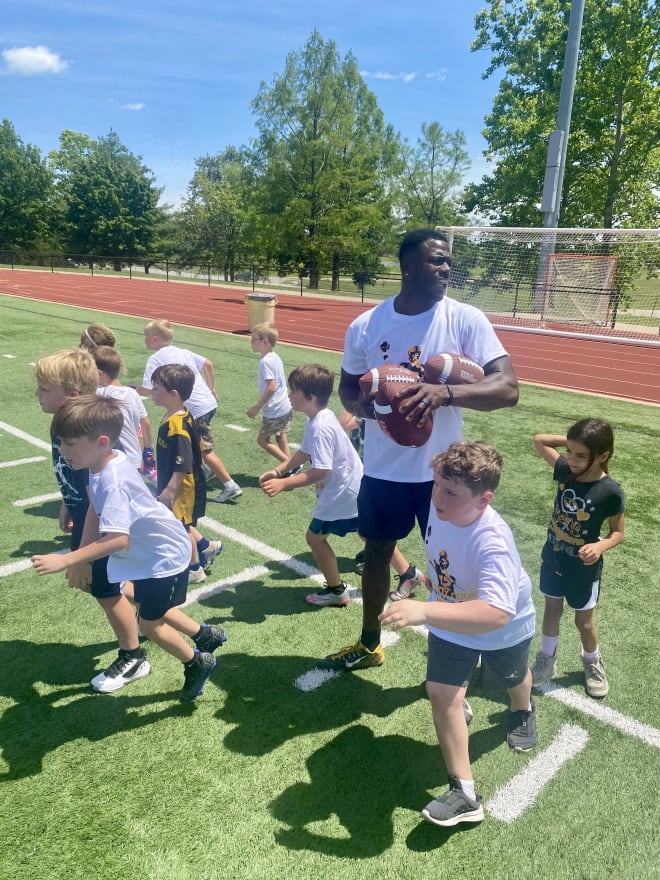 Jackson leads a group of kids, including Elliot Cox (front center with gray shoes), in one of the drills at the Brady Cook Youth Football Camp