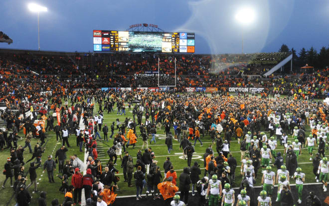 Oregon State fans rush the field as the dejected Ducks walk off of it