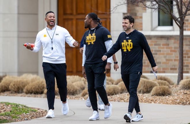 Head coach Marcus Freeman (left) shares a laugh with assistant coaches Mike Mickens (center) and Marty Biagi ahead of Notre Dame's first spring practice last Thursday.