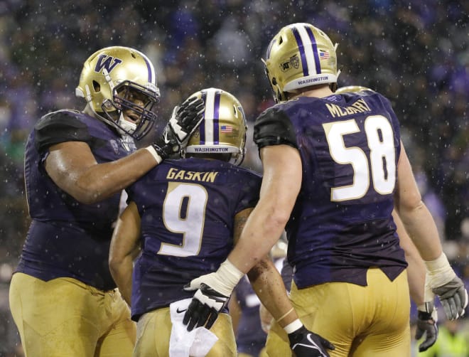 Washington running back Myles Gaskin (9) is greeted by offensive linemen Andrew Kirkland, left, and Kaleb McGary, right, after Gaskin scored a touchdown against Washington State during the second half of an NCAA college football game, Saturday, Nov. 25, 2017, in Seattle. (AP Photo/Ted S. Warren)